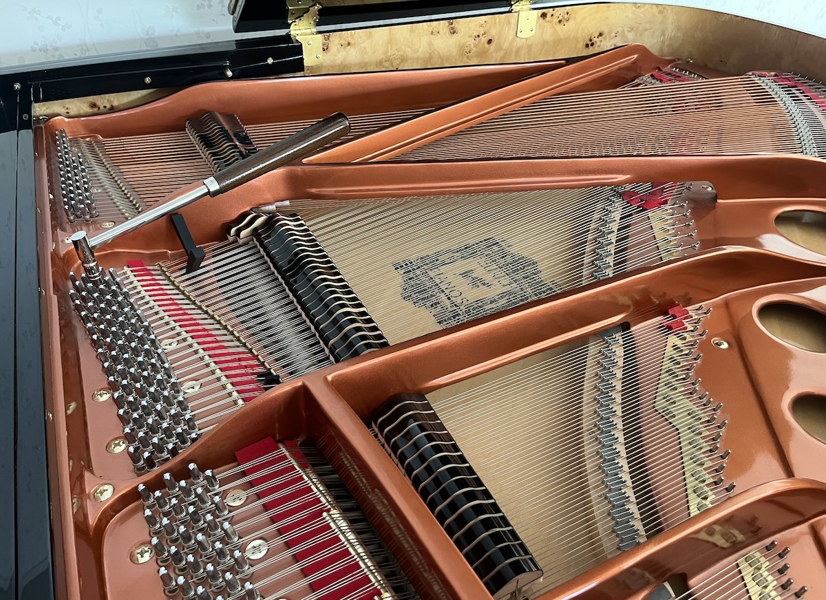 Inside of a grand piano with tuning equipment